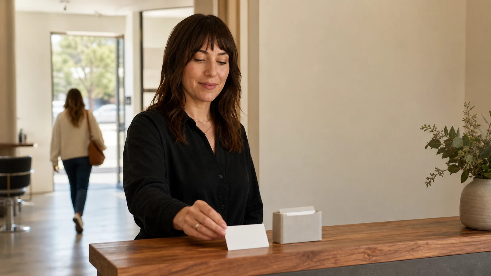 Salon owner leaving an optional review-request card at reception after a completed visit